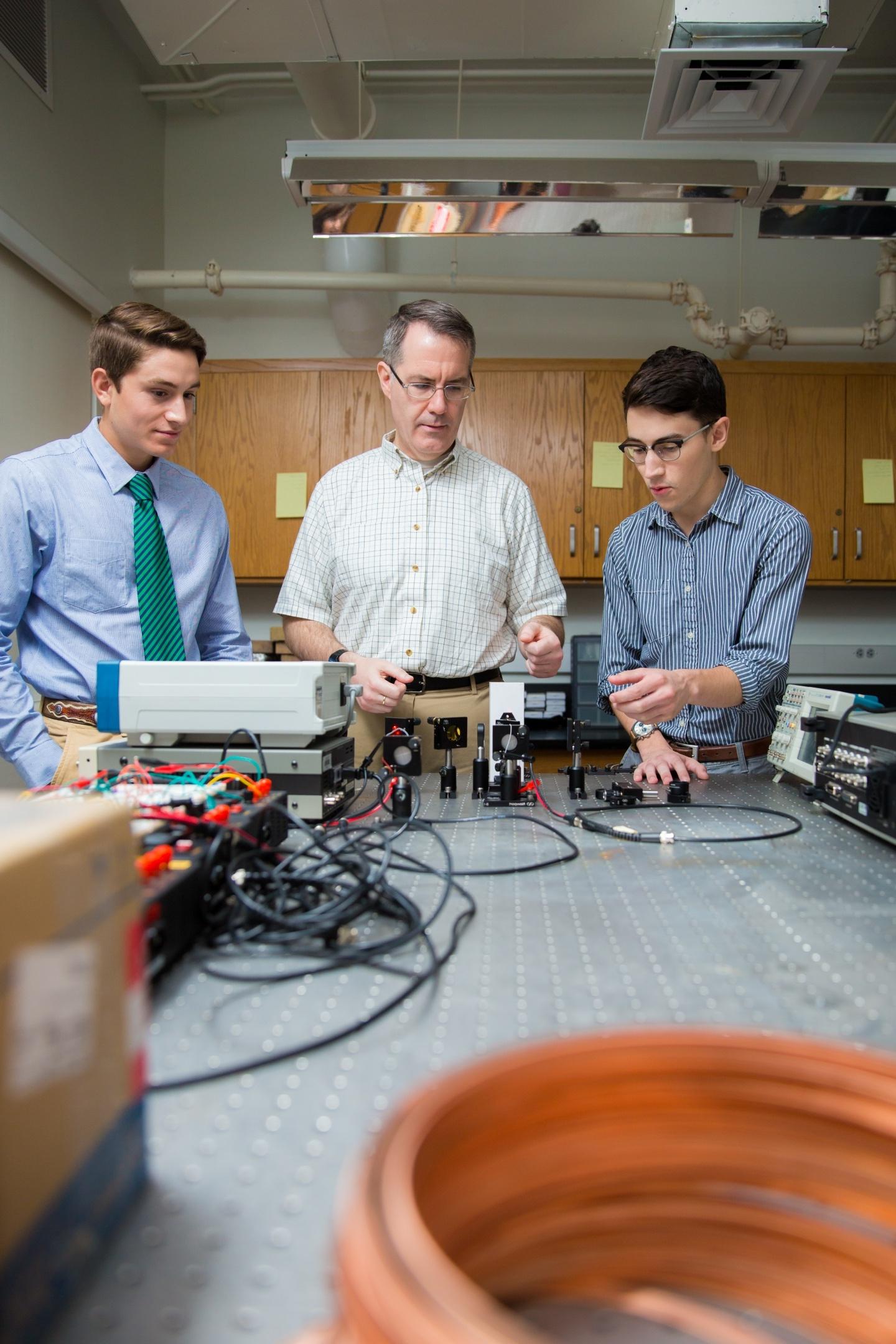 Professor and two male students using equipment